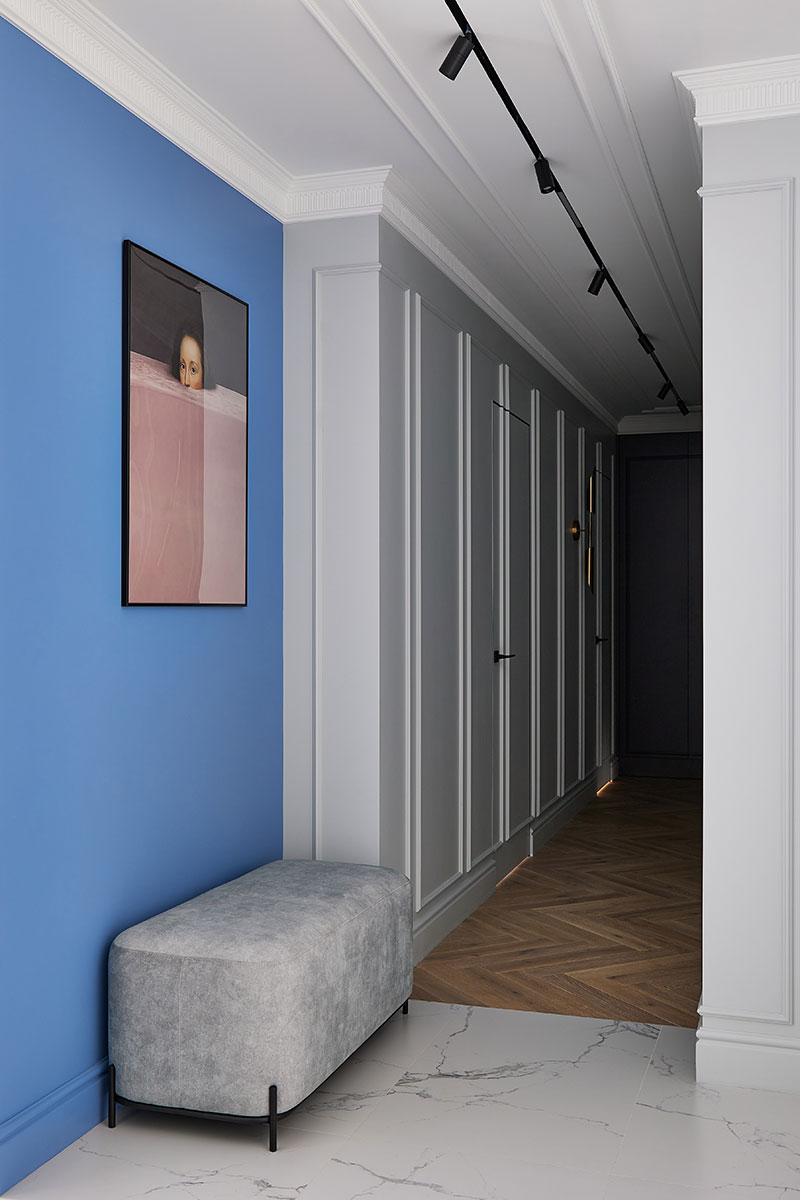 Фото коридора с голубой стеной и мягким серым пуфом