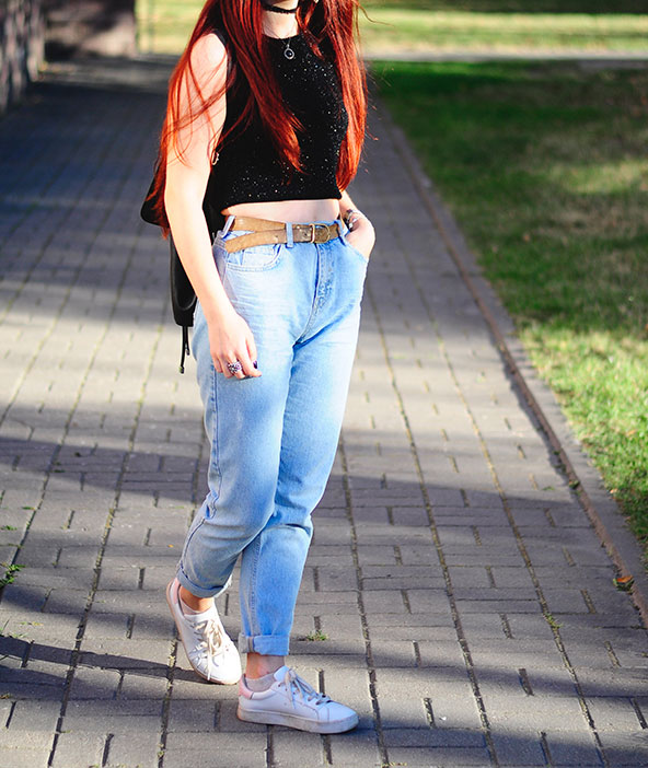 Девушка в джинсах с завышенной талией и кроп-топе.
