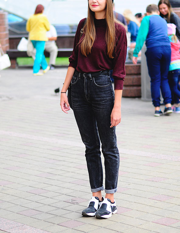 Девушка в джинсах с завышенной талией и бордовом свитере.