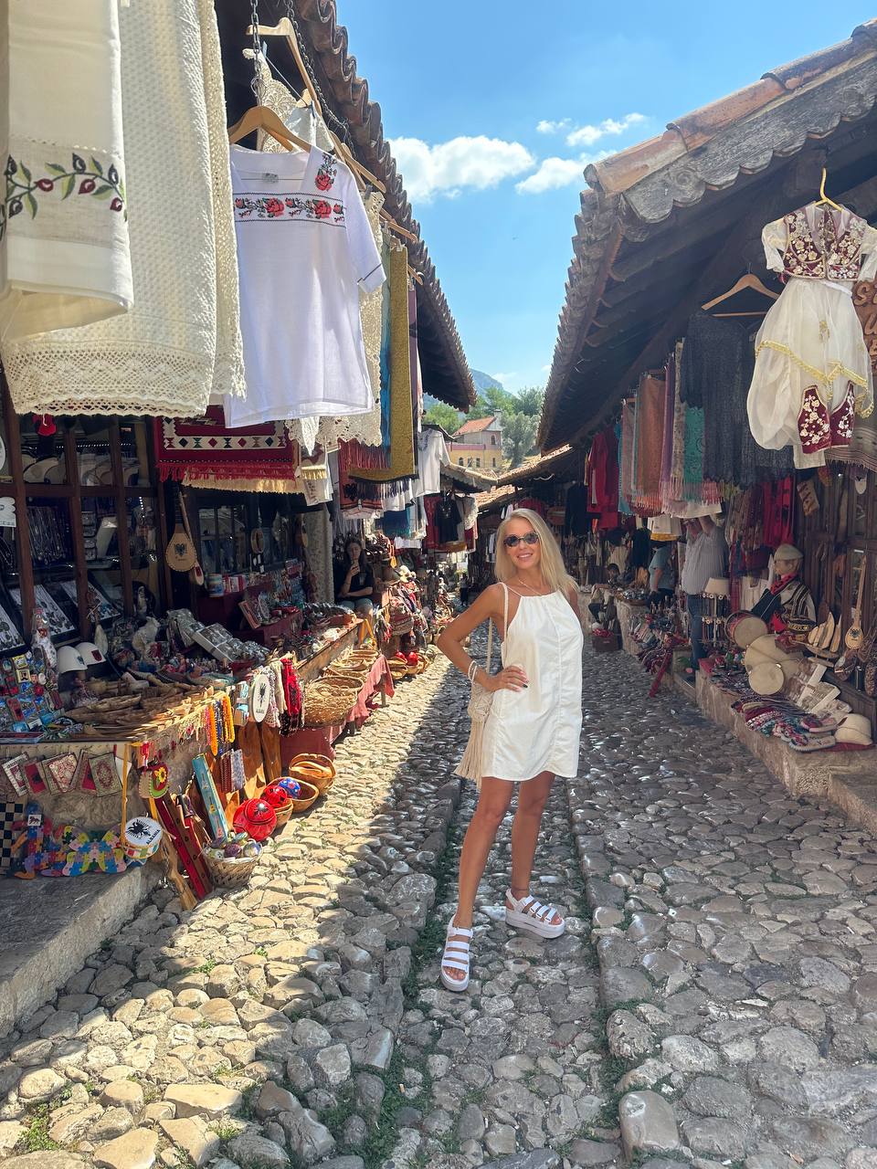 Городской рынок в Албании и девушка в белом платье.