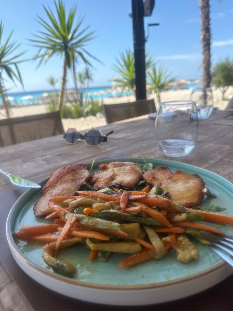 Тарелка с овощами на фоне моря и пляжа.