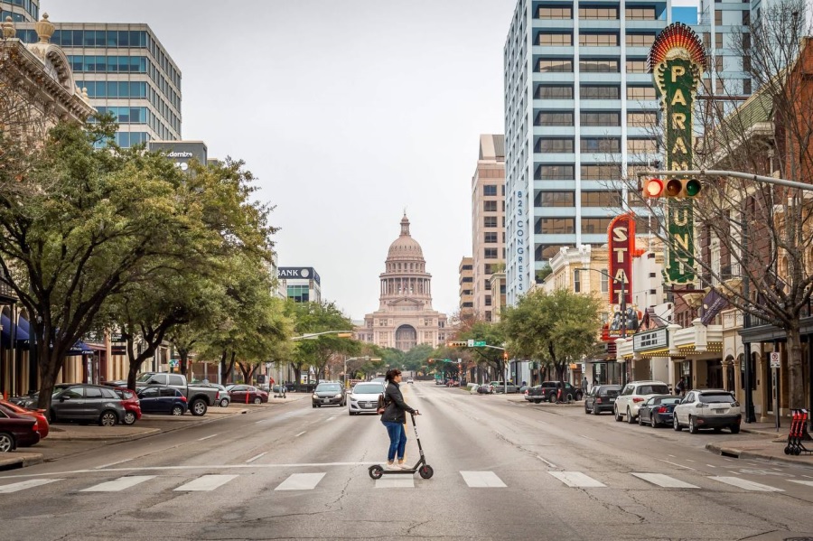 Остин, щтат Техас. Девушка на самокате едет по пешеходному переходу.