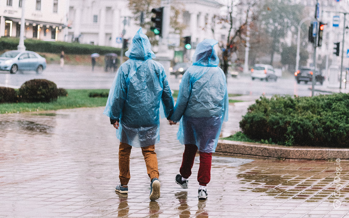Пара гуляет в дождевиках по площади Свободы в Минске.