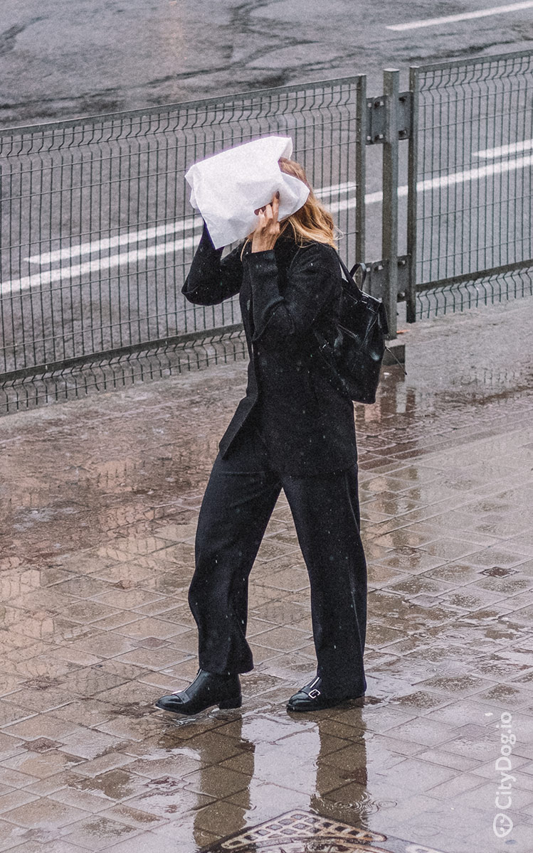 Девушка прачет голову под пакетик во время дождя на Немиге.