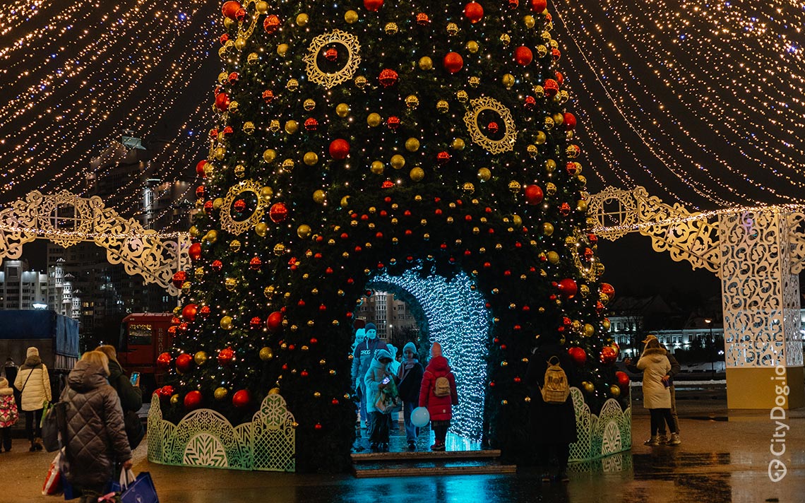 Люди фотографируются на фоне новогодней елки.