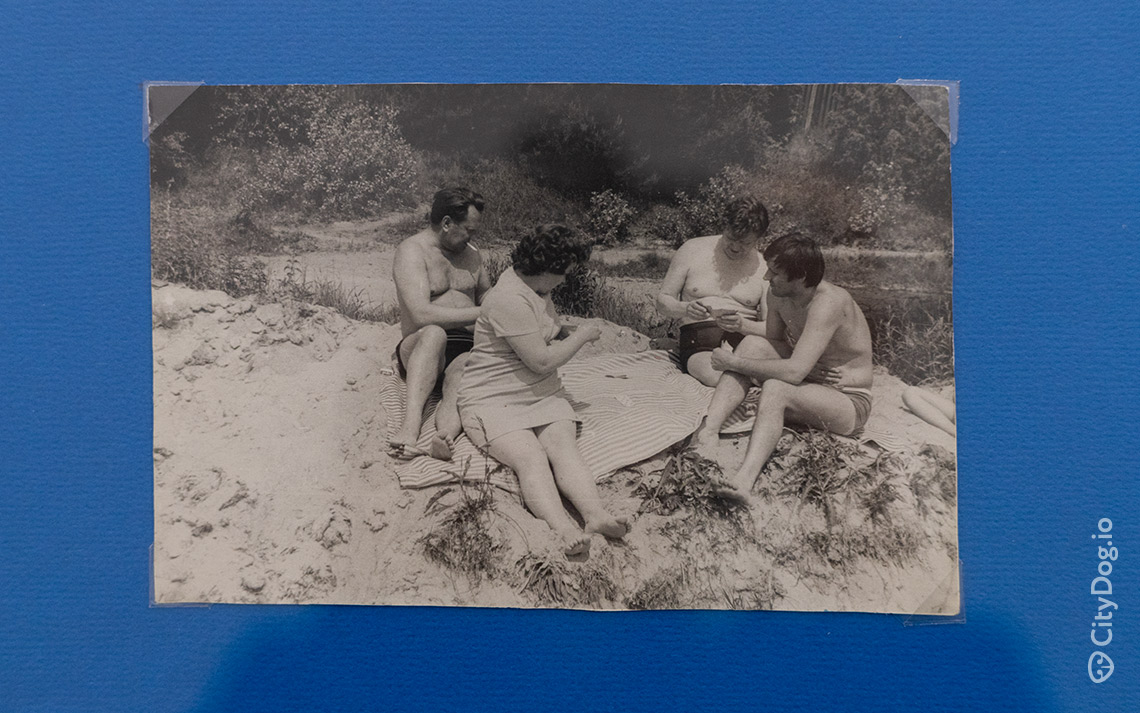 Четыре человека играют в карты, сидя на песчаном пляже.