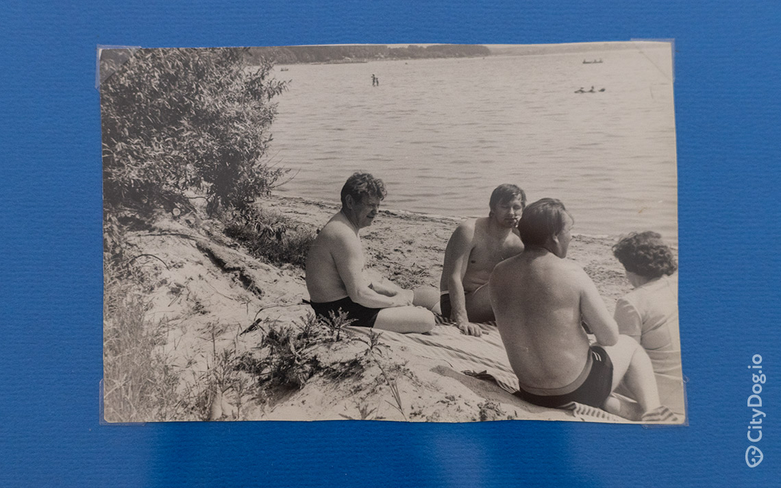 Трое мужчин и женщина отдыхают на берегу озера.
