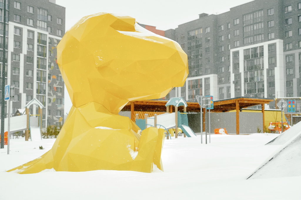 Желтый динозавр на снегу.
