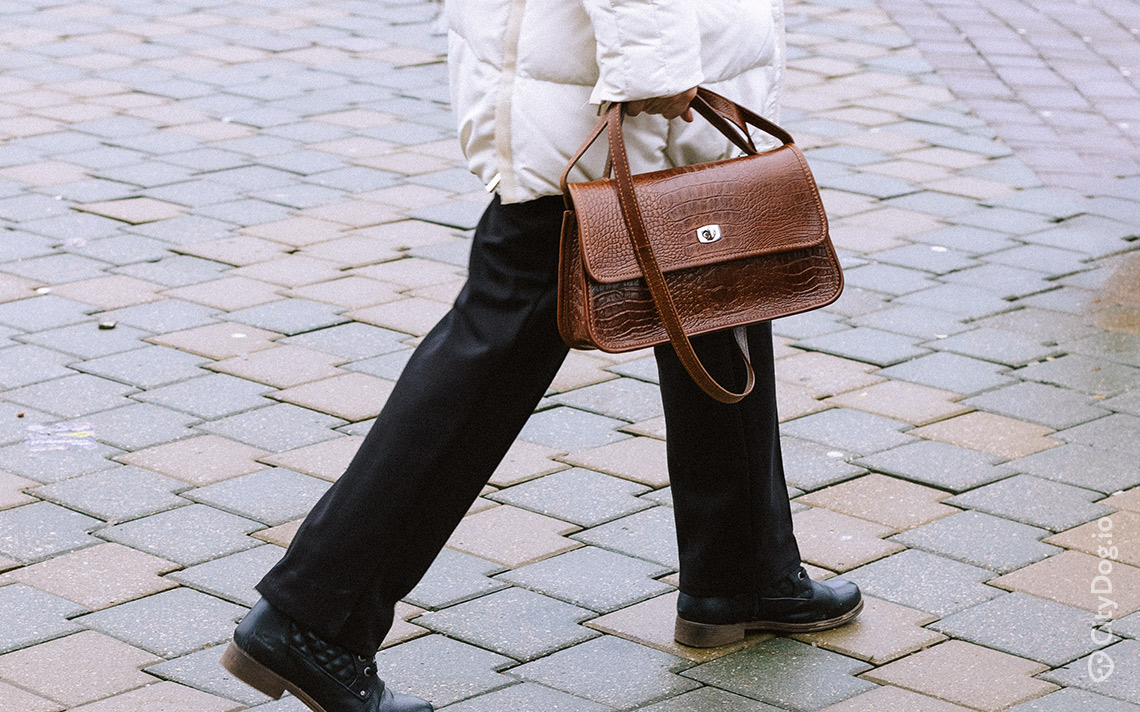 Женщина с коричневой небольшой сумкой.