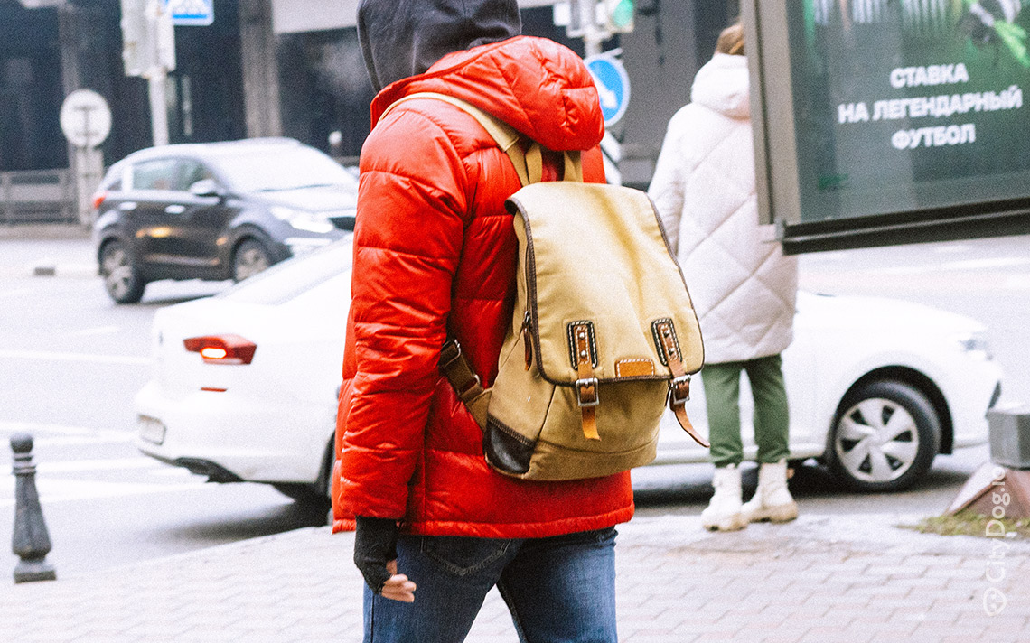 Человек в красной куртке и с желтым городским рюкзаком.
