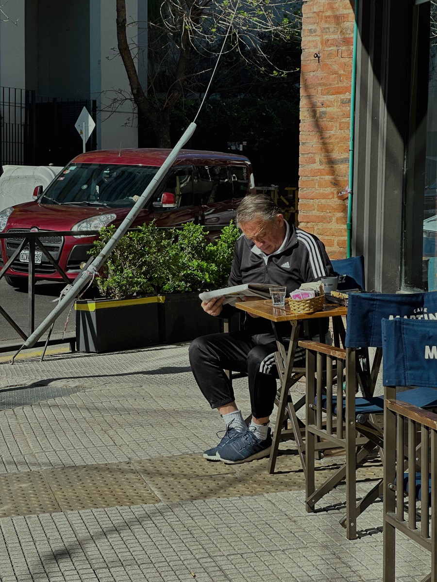 Аргентинец читает новости в кафе на улице.