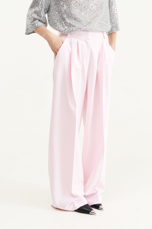 Свободные розовые брюки бренда MUA, которые девушка сочетала с блестящей футболкой в пайетки. 