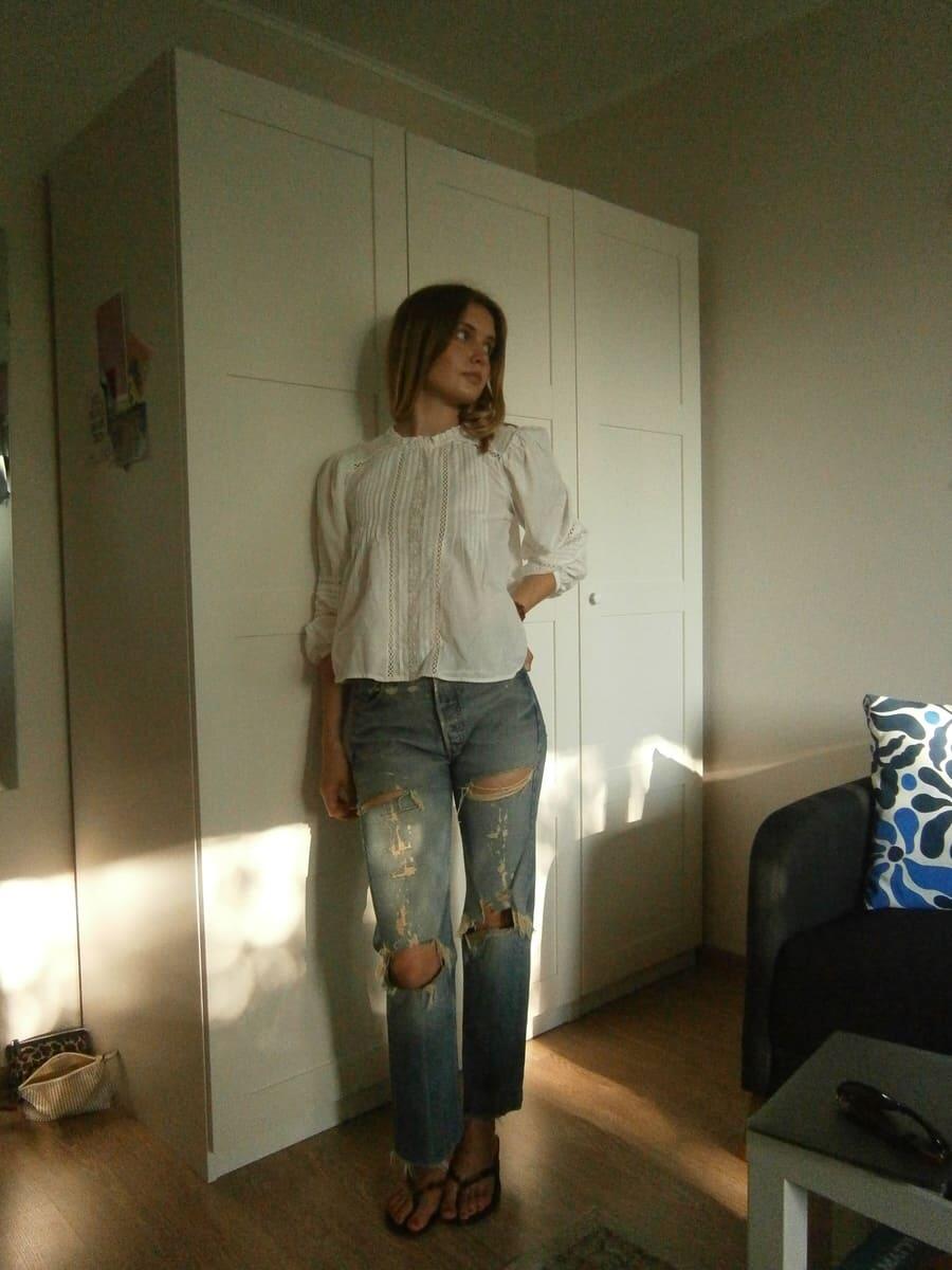 Девушка в белой рубашке из H&M и рваных джинсах Levi’s.